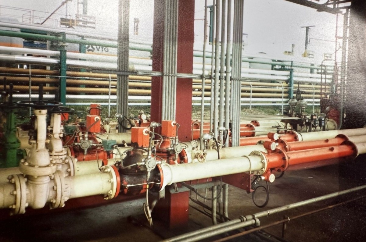 Een verzameling leidingen en ventielen in een industriële omgeving, met verschillende kleuren en onderdelen zichtbaar.