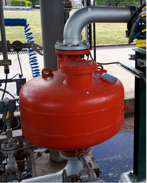 Een grote, rode vloeistoftank met een metalen uitlaatpijp en aansluitingen, geplaatst op een industri&euml;le locatie.