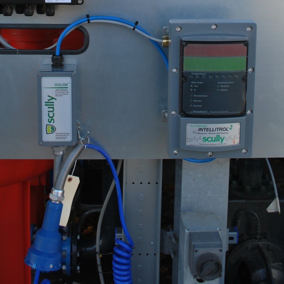 Scully-intelligentie controlesysteem met een junction box en een blauw aansluitpunt op een metalen wand.